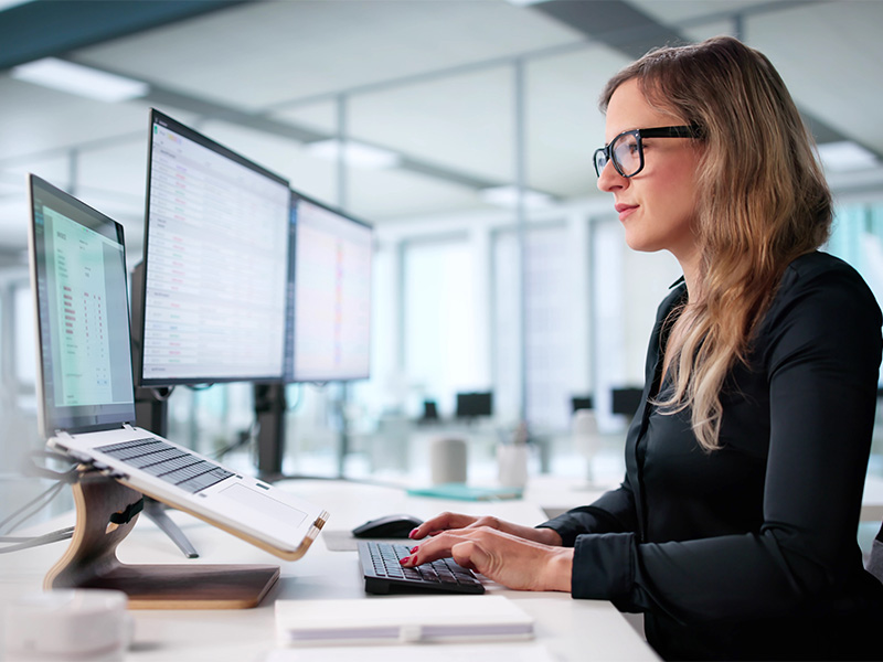 Junge Mitarbeiterin im Lohnbüro erfasst Daten am Computer zur Erstellung der Lohnabrechnung professionell und genau.